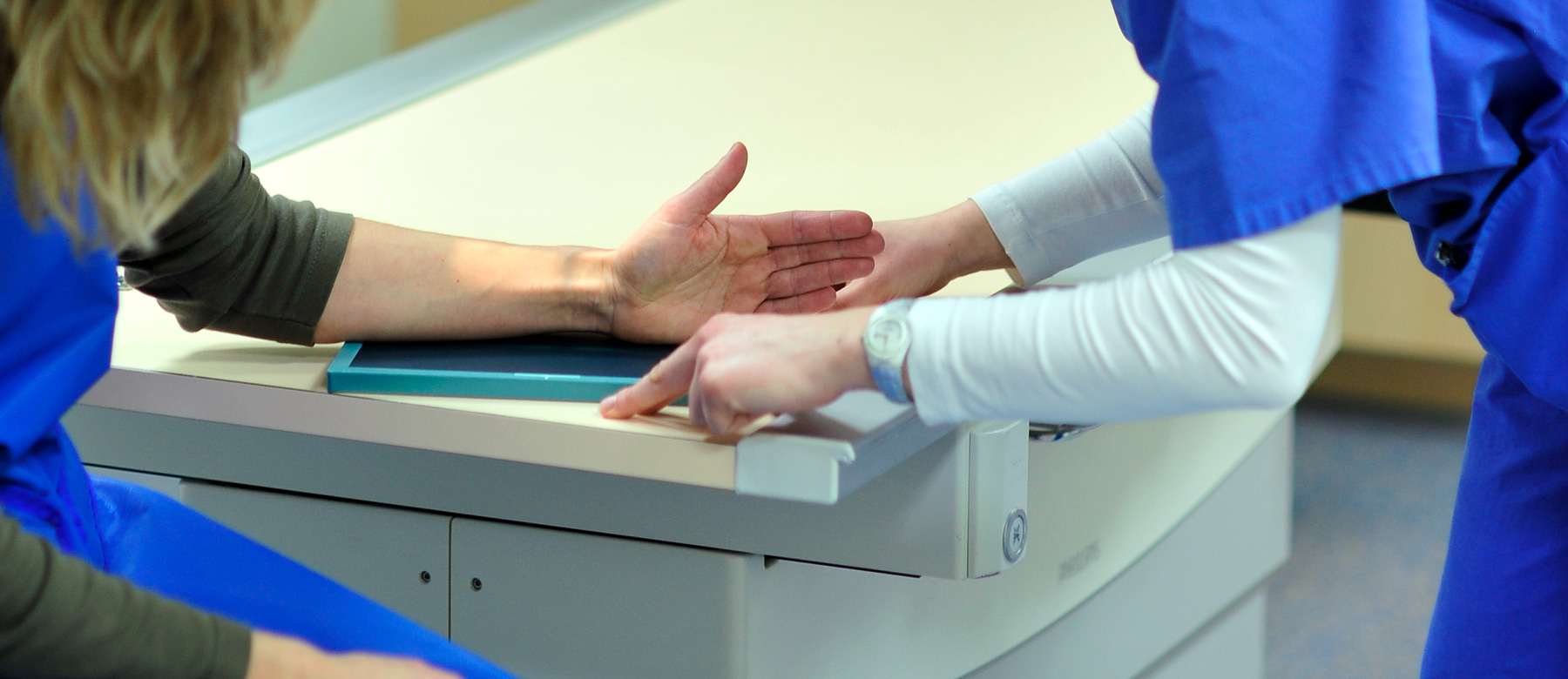 Mitarbeiterin der Abteilung für Radiologie und Neuroradiologie richtet die Hand einer Patientin fürs Röntgen aus.